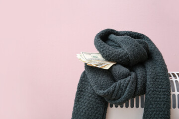 Warm scarf with money on electric convector heater near pink wall at home. Heating saving concept