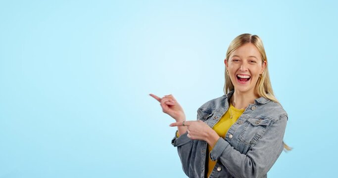 Woman, point and happy in studio, space or mockup with review, choice or direction by blue background. Student, girl and sign with face for decision, feedback and deal on promo, announcement or sale
