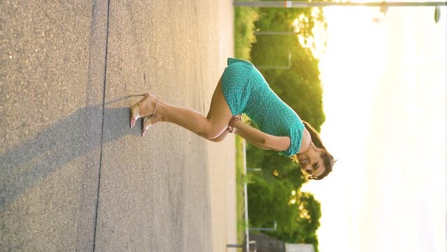 Romanian Romani European Gypsy woman twerking on a street without any hesitation feeling confident in her skin wearing green dress and heels messy hair slow motion sunset setting turning around sexy