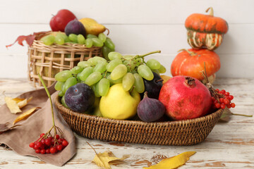 Wicker basket with different fresh fruits on white wooden background