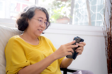 Happiness senior woman retirement using smartphone video call in living room at home, happy elderly watching message or social media on smart phone online with satisfied, lifestyles concept.