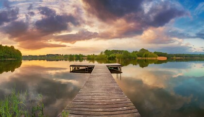 panorama landscape wooden pier on the lake at sunset clouds reflection in the water