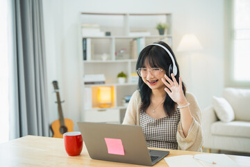 Business freelance entrepreneur woman wearing eyeglass and white headphone say hi while conference...