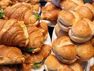 Stack of Hearty Sandwiches and Croissants with Savory Meats, Fresh Greens and Melted Cheese