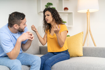 Young latin couple arguing sitting on the sofa