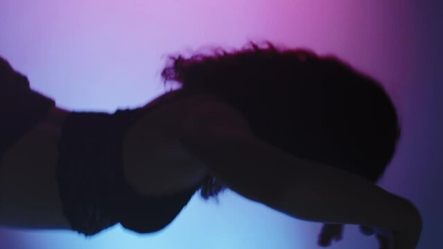 Vertical video. Modern choreography. Professional dance. Graceful sensual artistic woman in black lace bralette moving on purple neon light background.