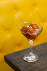 Sweet dessert is served against a yellow booth seat in a modern Indian restaurant. 
