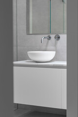 A white sink is seen in a sleek, bright, modern bathroom.