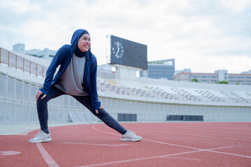 Fototapeta na wymiar A young asian Muslim woman wearing a black hijab is exercising and running at an outdoor stadium in the morning. Modern Muslim woman concept, Muslim woman sport concept, Islam