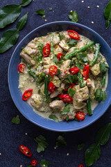 A freshly made bowl of Thai green chicken curry is served with green beans and red chillies.