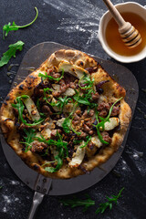 Freshly made wood-fired pizzas rest on a metal paddle placed on a stone bench top. 