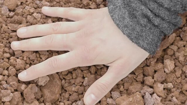 Close-up of a woman's hand sensually touching volcanic gravel (slow motion)