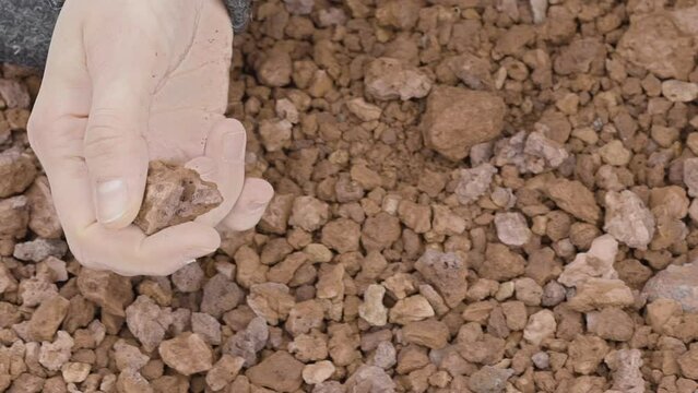 Close-up of a woman's hand sensually playing with volcanic gravel (slow motion)