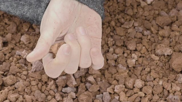 Close-up of a woman's hand sensually playing with volcanic gravel (slow motion)