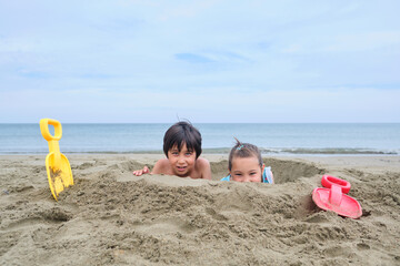 Children dig a hole in the sand on the seashore.