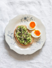 Delicious breakfast, snack, brunch toast with avocado, pumpkin seeds and boiled egg on a light background, top view