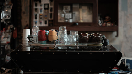 Variety of cups and glass above the espresso machine on the rustic industrial coffee shop