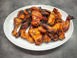 Golden grilled marinated chicken wings and thighs on white plate