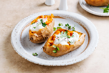 Whole baked sweet potatoes with spices, herbs and sour cream. Selective focus.