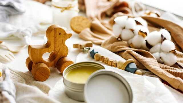 Baby supplies, a wooden duck and cosmetics for the care of newborns on the background of children's things.
