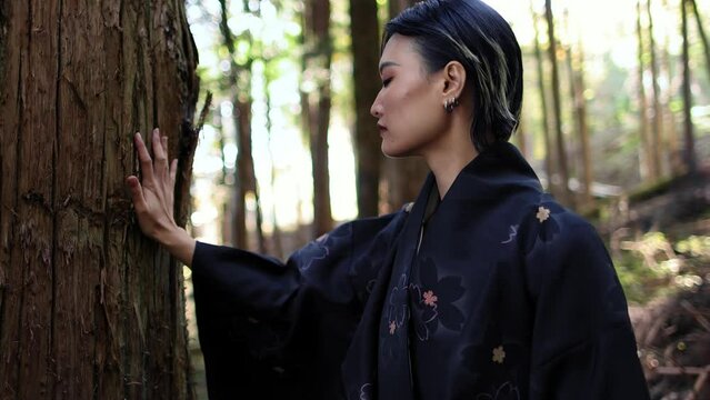 beautiful asian woman in a kimono in a forest in Japan touching a huge cedar tree trunk, harmony with nature, shintoism in Japan, shinto prayer