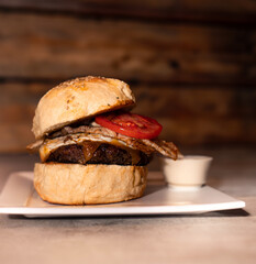 Fototapeta na wymiar Burger with Egg, Cheese, and Tomato on Wooden Background