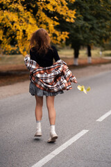 young girl running along the road, autumn atmosphere, photo from the back