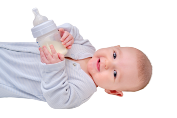 Happy baby is smiling on her own holding a bottle of milk in her hands, isolated on a white background. Three month old child keeps the mixture himself lying in bed