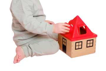 Happy toddler baby plays sorter with geometric shapes on studio, isolated on white background. Child boy plays educational toys, isolated on white background. Kid age one year eight months