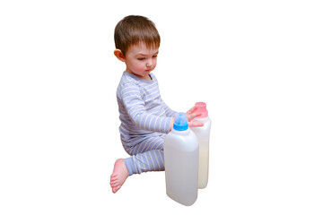 Toddler baby plays with household chemicals and detergent from the closet, isolated on white background. Child boy with detergent bottle in home living room. Kid age one year nine months