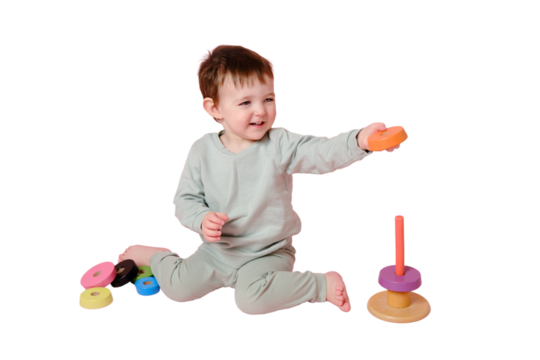 Happy toddler baby plays with a pyramid on a studio, isolated on white background. Child boy puts wooden rings on a toy pyramid. Kid age one year eight months, full height