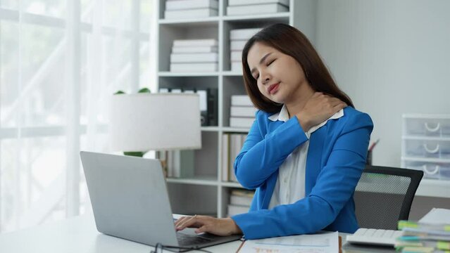 Office Asian business woman stretching body for relaxing while working with a laptop computer at her desk, office lifestyle, business situation.