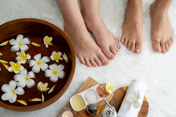 Couple indulges in blissful foot massage at luxurious spa salon for reflexology therapy in gentle day light ambiance resort or hotel foot spa. Quiescent