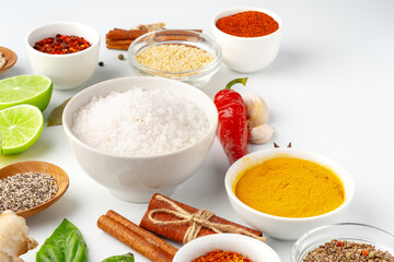 Bowls with spices and cooking ingredients on white background