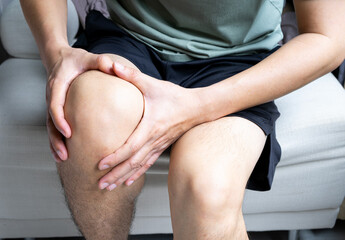 Man with knee pain, he puts his hand on his knee, pain point from osteoarthritis and...