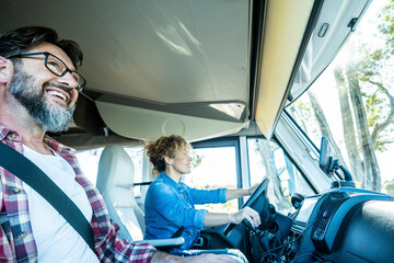 One woman driving modern rv camper van vehicle with happy man on her side as passenger. Happy...