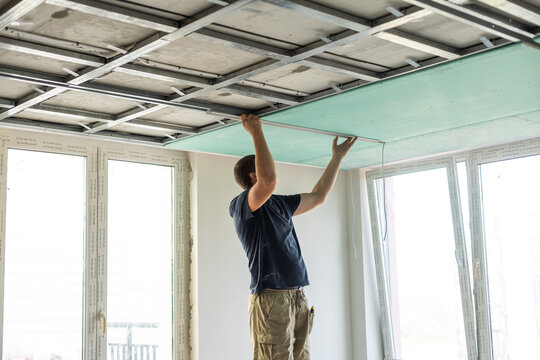 Man assembles profile metal frame for plasterboard ceilings