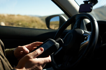 A man with a GPS navigator in his hands inside a car in the mountains. Excerpt.