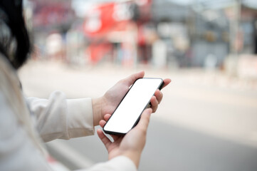 Close-up image of a woman using her smartphone while walking down the street in the city.