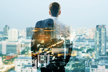 Back view of young male silhouette looking into the distance on creative night city background....