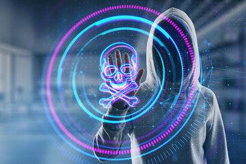 Hacker in hoodie using creative digital round skull hologram on blurry office interior background. Hacking, piracy and malware concept. Double exposure.