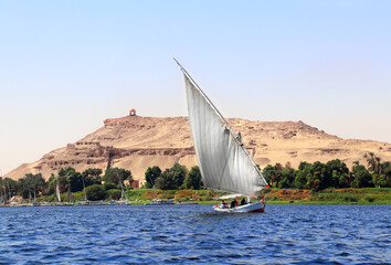 Traditional sailing boat felucca, Nile river near Aswan, Egypt. A famous tourist attraction - sailing boat ride