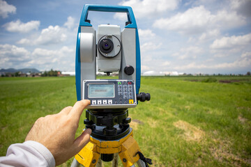 point of view of a caucasian land surveyor engineer measuring a field using a total station surveying equipment; close up of a hnd hand using a survey instrument working with a theodolite