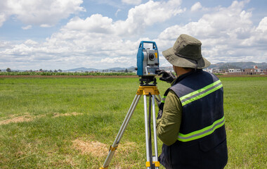 unrecognizable hispanic land surveyor engineer measuring a field using a theodolite surveying...