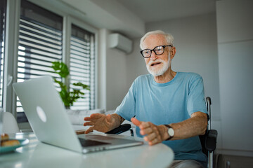 Senior man in a wheelchair shopping online on laptop. Online financial scam targetin older people....