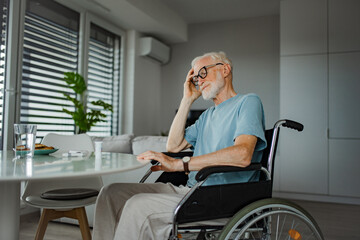 Senior man in wheelchair taking pills at home, he is confused about mediacation usage. Chronically...