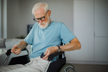 Senior man checking his blood sugar level on insulin pump. Close up of senior man in wheelchair...