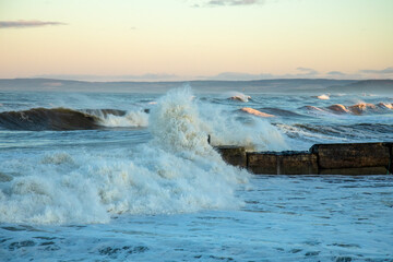 Storm hitting the coast of Scotland with crashing waves coming over a harbour wall