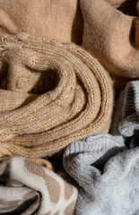 Rolled knitted sweaters closeup. Autumn or winter background. Autumn or winter season, sale. Stack of cashmere clothes. clothes made from natural materials.