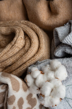 Folded knitted sweaters with cotton flowers .Autumn or winter season, sale.Stack of cashmere clothes. clothing made from natural materials.Close-up of knit texture.